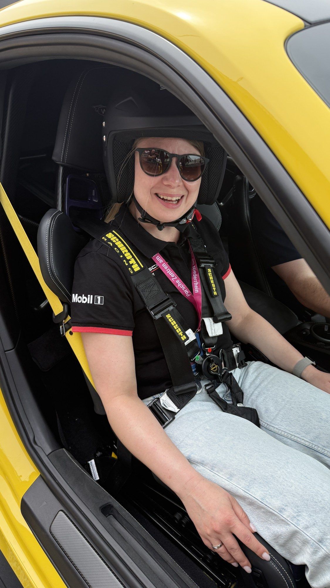 Lachender Gast mit Helm auf dem Beifahrersitz eines Sportwagens
