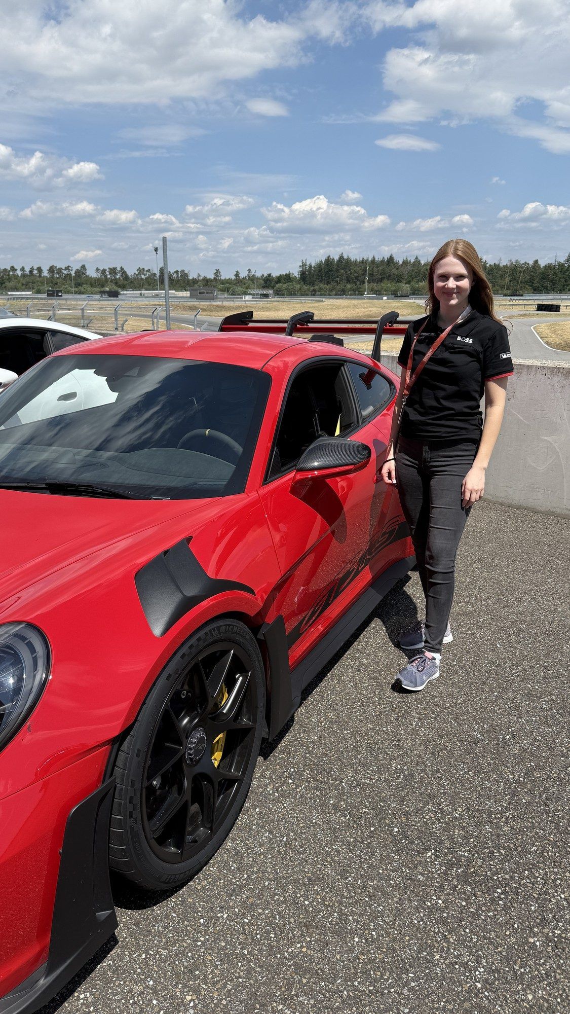 Teammitglied neben einem roten Porsche GT3 RS an der Rennstrecke